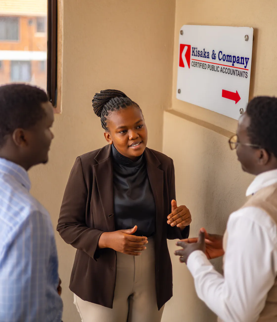 Three Kisaka colleagues in conversation beside the Kisaka & Company sign
